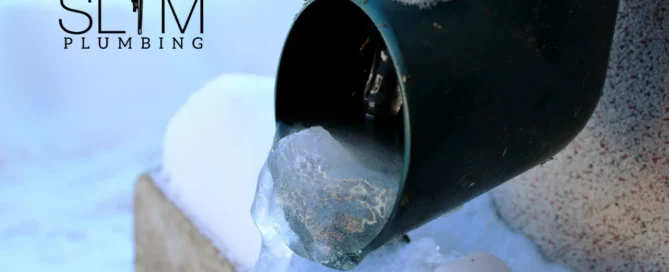 Prevent Pipe Bursts in Freezing Weather — pipe covered in snow with ice forming and water freezing around the line.